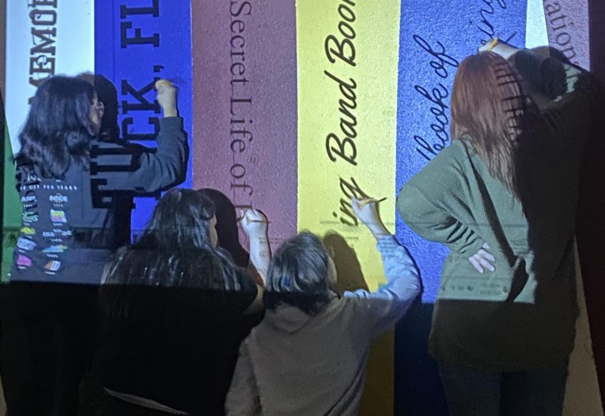 Valerie Trejo-Lopez, 12, Charity Gray, 11, Katelyn Humphrey, 12, and Madison McCurry, 11, trace lines for words on book covers using a projector.