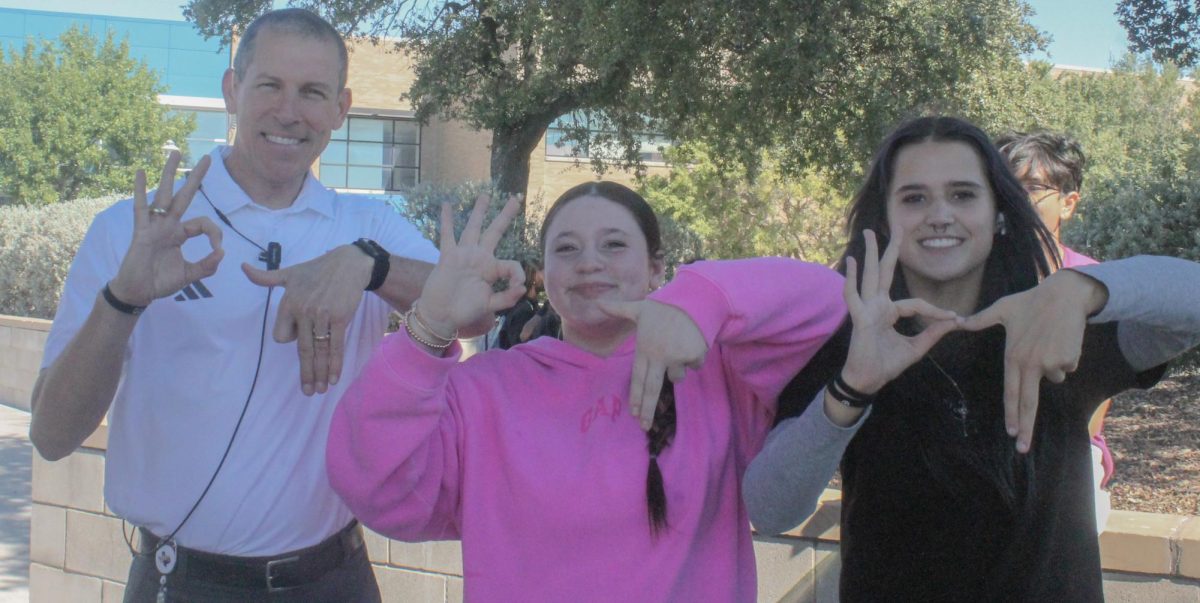 Six-Seven! Juniors Kylie Sandoval and Tegan Blaha teach Principal Ryan Wilson the "6-7" hand symbol 